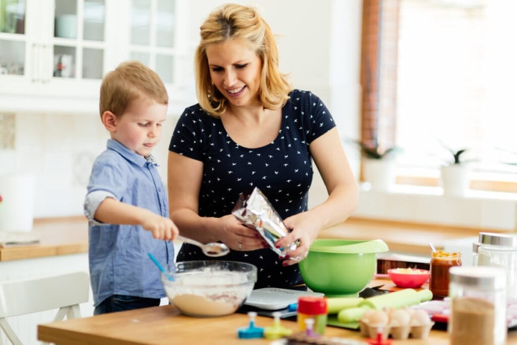 Child helping mother prepare muffins in kitchen
